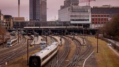 Aarhus Hovedbanegård med Bruuns galleri bagved og tog kørende ud af stationen